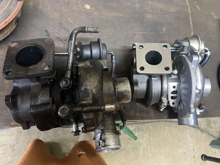 A worn turbo next to its brand-new replacement on the workshop bench